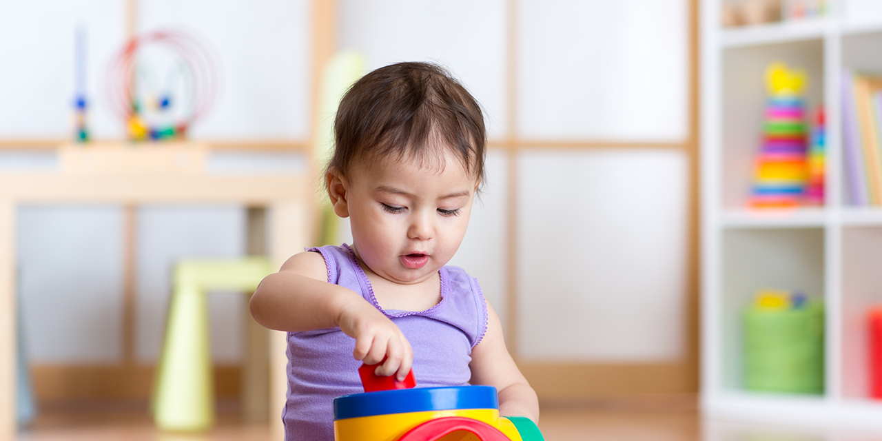 Toddler playing with toys while sitting on the floor.